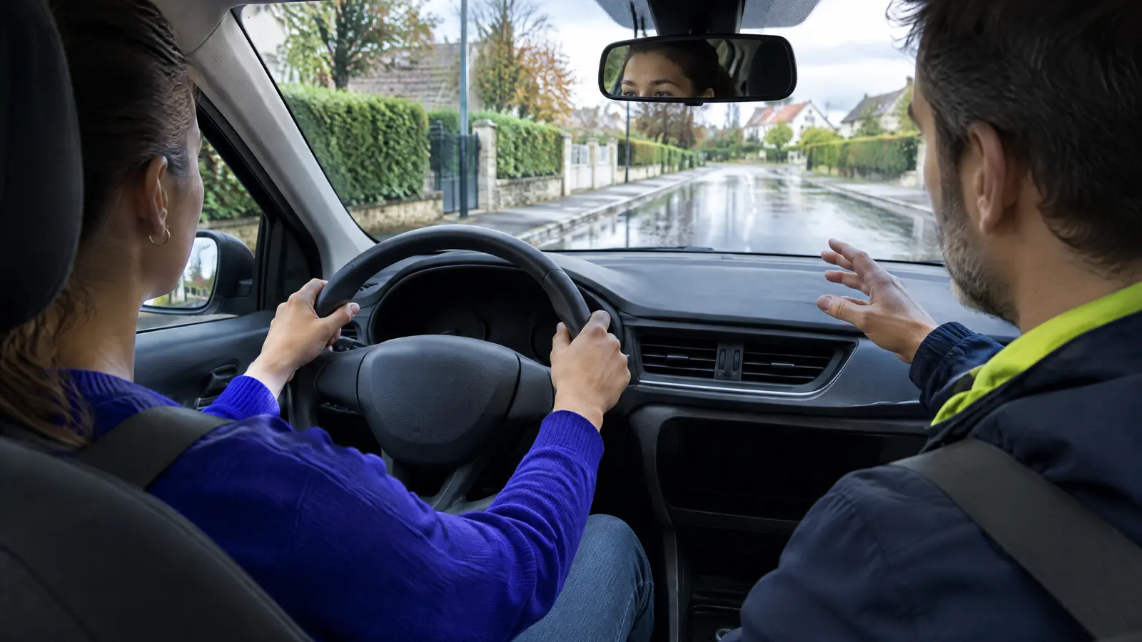Élève en conduite supervisée auto-école avec son accompagnateur sur route humide